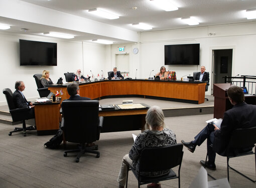 Powell River City Hall Council Chambers with 6 mayor and council members in a meeting, staff and attendees listening.