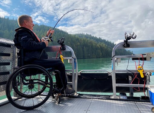 Side profile of Rick Hansen fishing from the back of a boat.