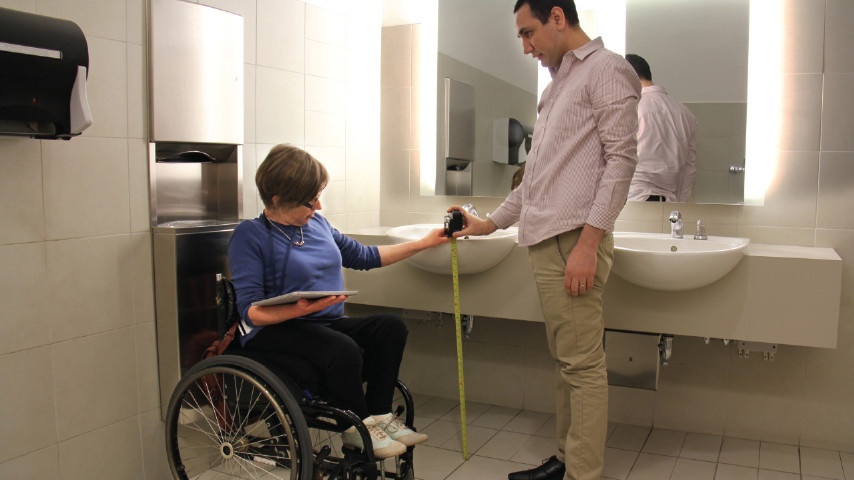 Two people measuring the height of a bathroom sink.