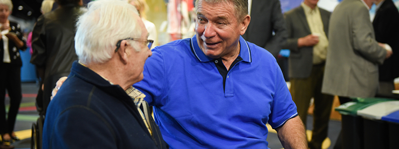 Rick Hansen talking to a man with white hair.