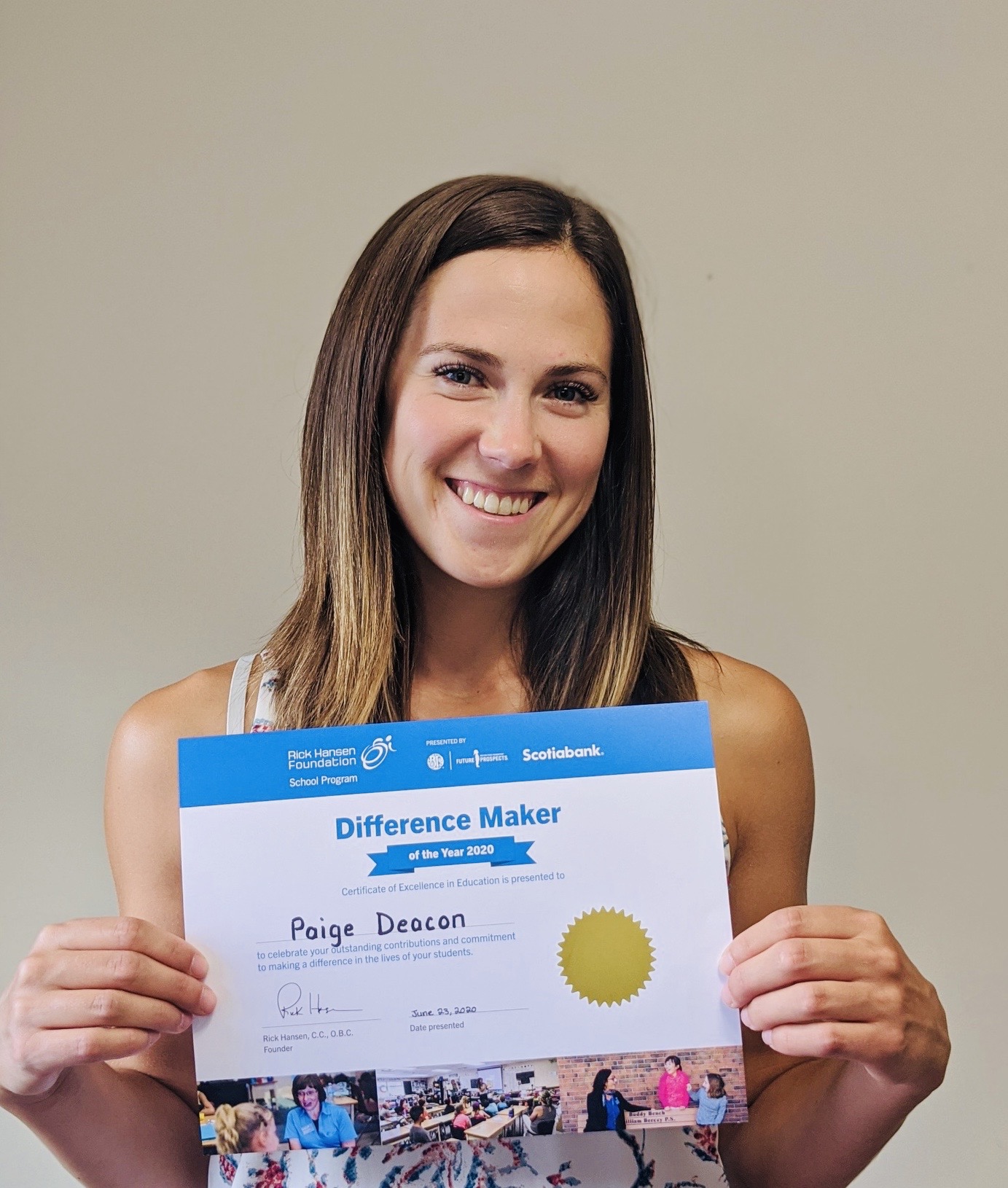 Young woman with brown hair smiles holding her certificate. 