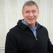 Man in front of a white building, smiling