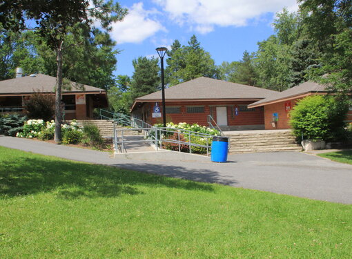 Brick building with accessible wheelchair ramp. The building is surrounded by green grass and trees.