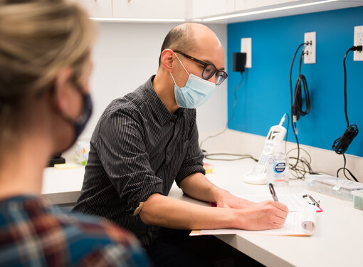 audiologist and patient, both wearing masks